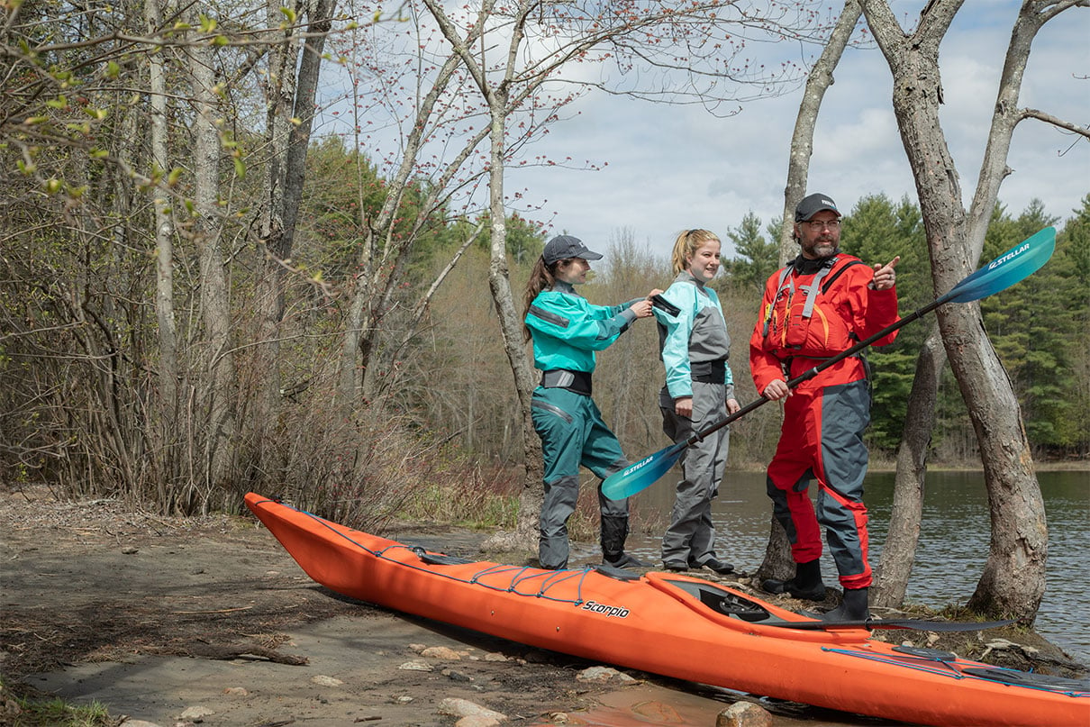 man and women put on drysuits while preparing for a kayaking excursion