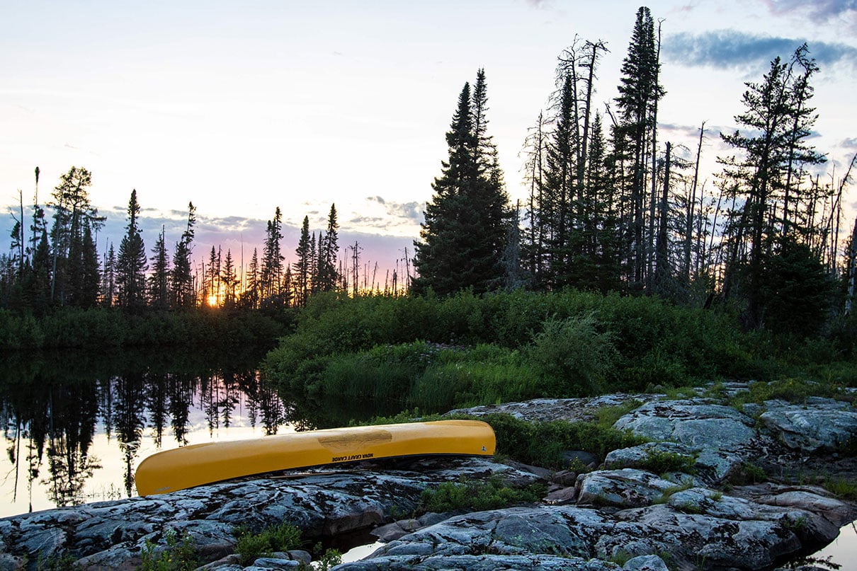 yellow canoe overturned at a rocky campsite in a northern forest