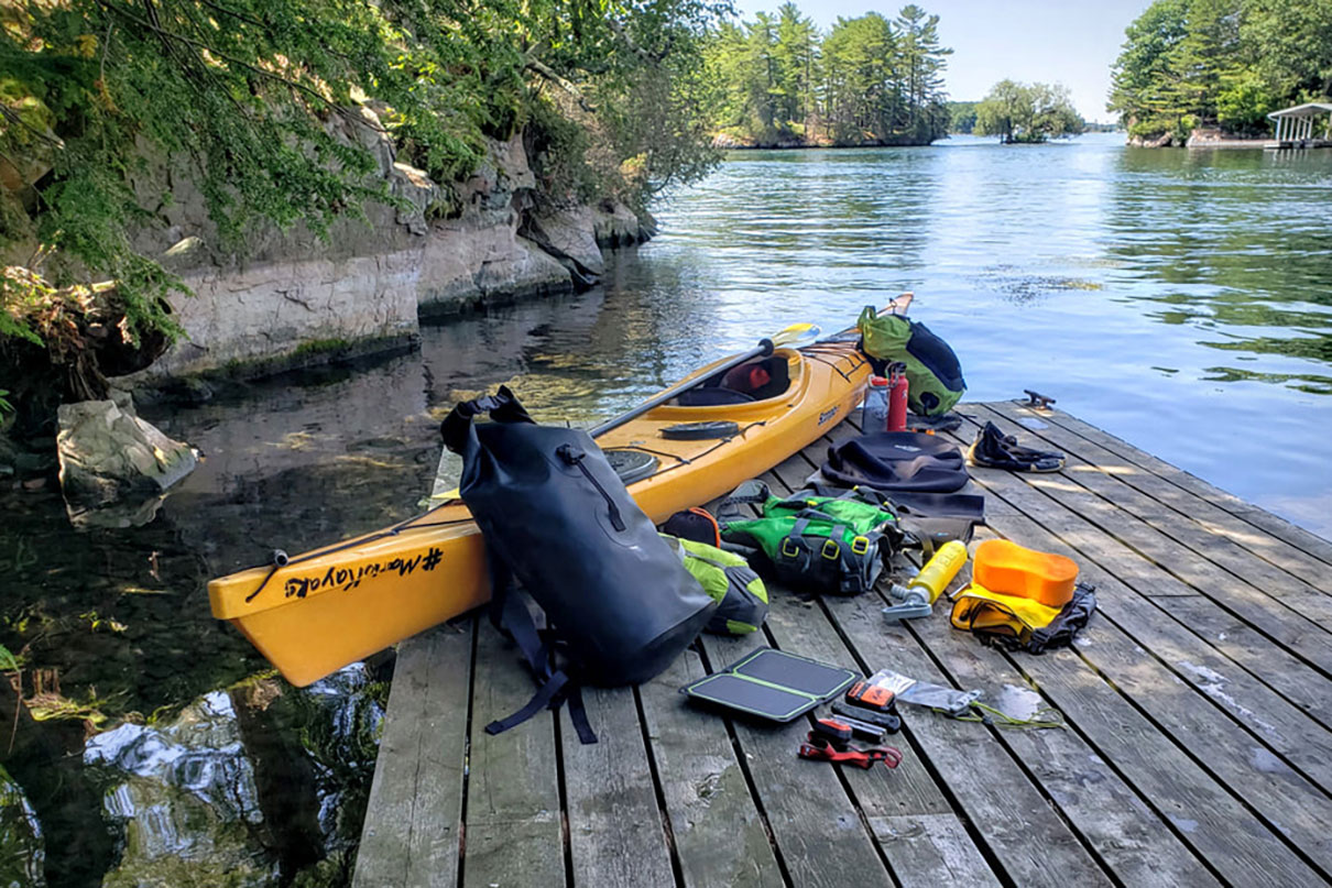 a kayak sits on a deck surrounded by gear