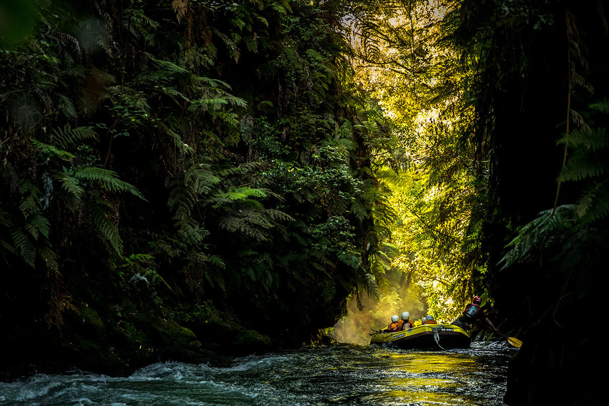 a rafting group heads down a dramatically lit river